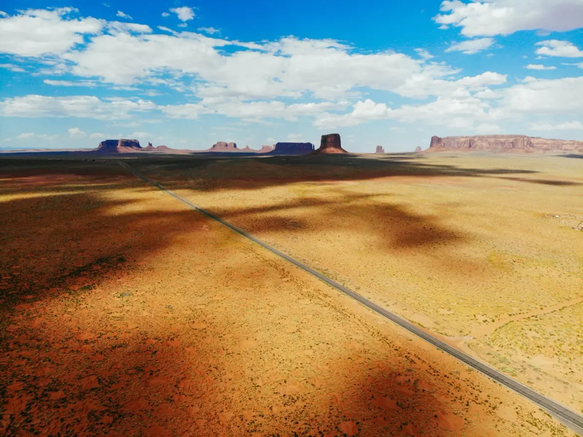 A highway crosses the desert toward the sandstone buttes of Monument Valley
